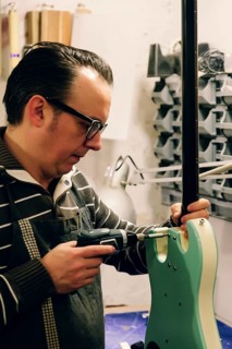 A skilled luthier focuses intently while assembling a bass guitar in a workshop, highlighting the
