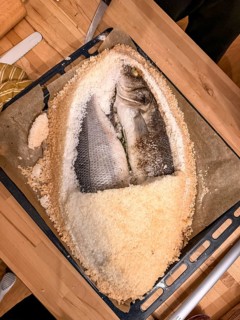 Fish in salt crust with opened salt crust on a baking tray, prepared by yourself, food photography,
