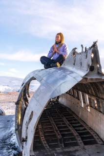 Woman sitting on the plane of Solheimasandur meditating in Iceland