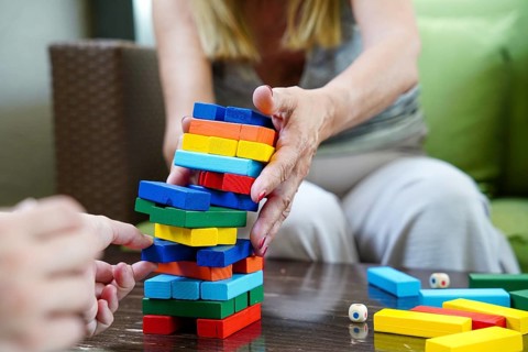 A close-up of hands carefully removing a block from a colorful stacking tower during a fun and