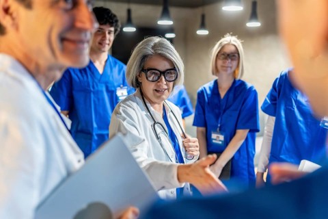Senior doctor explaining concepts to her medical team and students during an educational session,