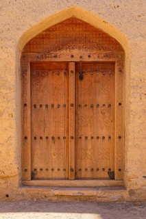 Decorated round arch entrance door in the largest preserved mud town in Oman, Al Bilaad, Al Bilaad