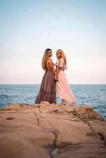 A couple of Caucasian girls with beautiful dresses, showing affection by the sea in summer
