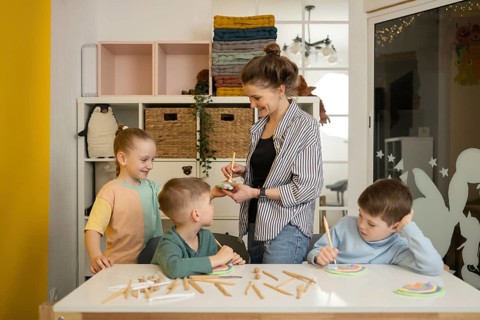 A teacher guides young children in a vibrant art lesson. The kids, engaged in crafting with