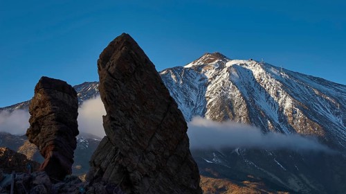 Roques de Garcia, massive rock formations against a snow-covered mountain under clear sky, Teide,