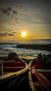 Two boats at sunset with golden sky and waves, romantic harbor scene, Ponta do Sol, Santo Antao,