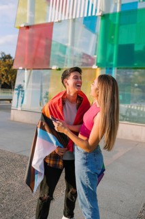 A joyful lesbian couple enjoys a sunny day wrapped in a pride flag, celebrating love and diversity.
