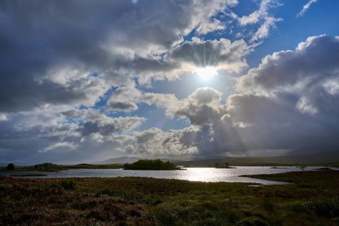Picturesque landscape with brightly lit lake under dramatic cloud formations, Rannoch Moor, Bridge