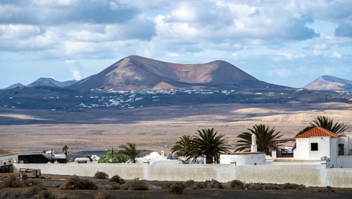 Volcanic landscape with volcanic cone, white houses in the village of Teguise, Lanzarote, Canary