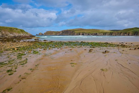Algae-covered rocks and sandy beach in front of a vast seascape, Farr Bay, Bettyhill, Thurso,
