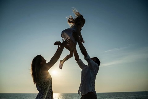 A family relishes precious moments on an Italian beach at sunset. With a serene horizon and playful