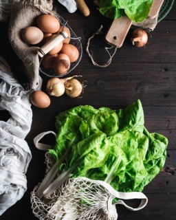Fresh vegetables including leafy greens and onions, with a basket of brown eggs, arranged on a