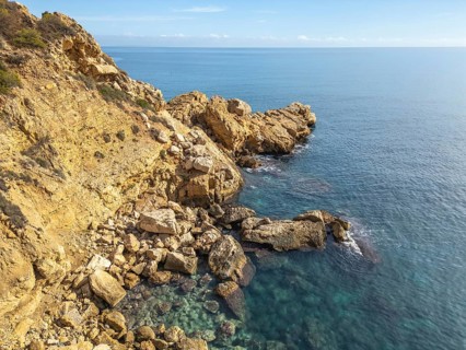 Stunning view of Costa Blanca's rocky coastline against a tranquil Mediterranean Sea. The rugged