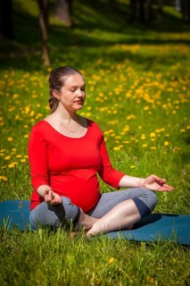 Pregnancy yoga exercise, pregnant woman meditating in yoga asana Sukhasana easy yoga pose with chin