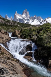 Chorrillo del Salto waterfall with view of Cerro Fitz Roy, snow-capped granite peaks against blue