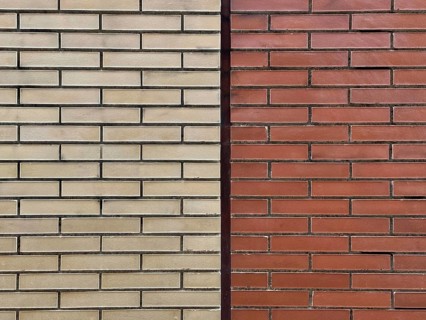 A close-up view of two contrasting brick walls, one beige and one red, highlighting differences in