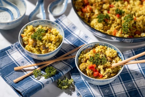 Dishes of fried rice and chopsticks next to the pan, decorated with parsley
