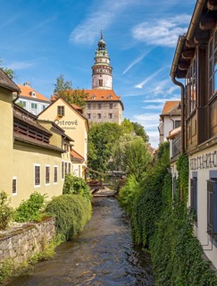 View of Ceský Krumlov Castle tower from a street with buildings and a stream, Cesky Krumlov, Czech