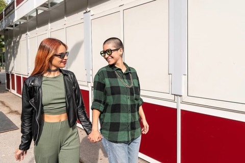 A Colombian lesbian couple holds hands, walking side by side, sharing a joyful moment while