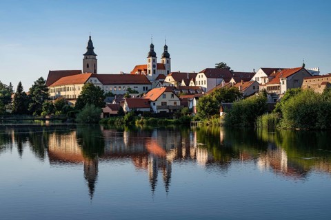 A wide panoramic view of the historic town of Telc with its colorful buildings and church towers