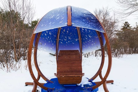 Interactive cocoon rocking chair made of curved wood and backlit blue tinted plexiglass panels
