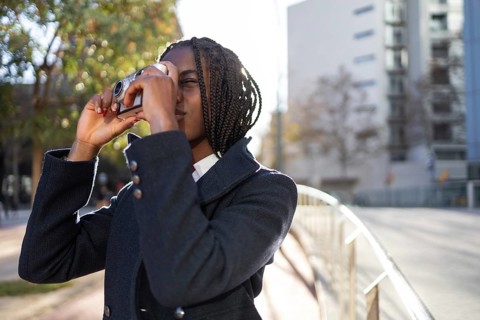An African American businesswoman with braids takes a leisurely break to engage in photography,