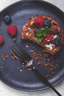 Half-eaten chocolate tartlet, on a plate, stuffed with cottage cheese and berries, breakfast,