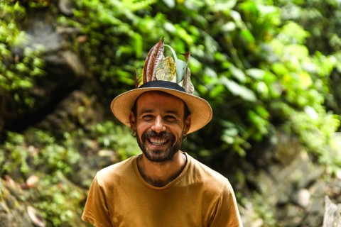 A cheerful Spanish young man beams joyfully in the Choco Andino rainforest of Ecuador, adorned with