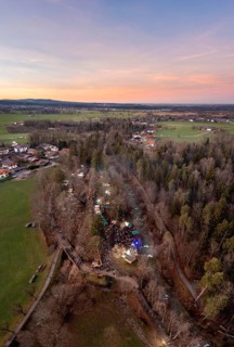 Aerial view of a rural landscape with trees and buildings in the evening light, showing a festive