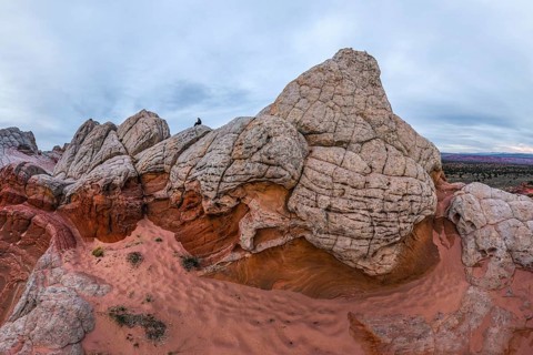 Unrecognizable individual perched on the striated rock formations of White Pocket, Arizona, USA,