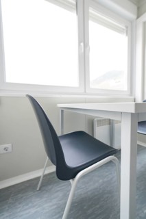 Bright room with a simple table and chair, window in the background, refugee accommodation Beermiß,