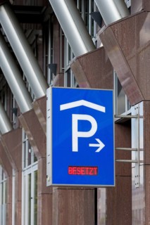 Blue car park sign with white P symbol and red display with the words 'Occupied' in front of modern
