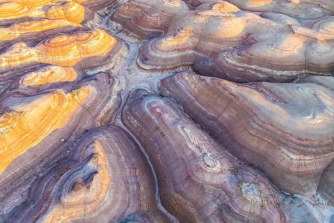An aerial view of the unique golden hues and layered formations of bentonite clay in Utah, USA. The
