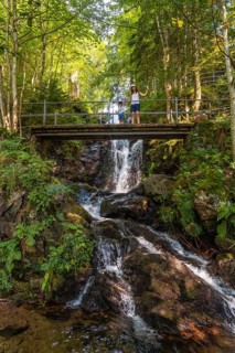 A mother and her son waving on a bridge at the Todtnau waterfall in the Black Forest in Germany