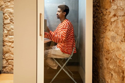 A man working in a soundproof cubicle in a coworking space. The environment combines privacy with a