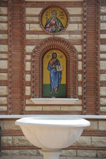 White baptismal font built in 1950 from stone, wall mosaic with Christ figure, Greek Orthodox St.