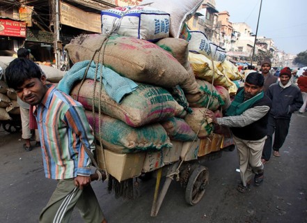New Delhi, India, 14.01.10 - Two men push a trailer loaded with bags, India