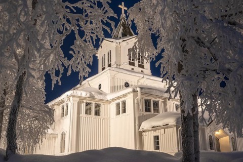 Illuminated wooden church with frost-covered birches, Gällivare, Norrbotten, Lapland, Sweden,