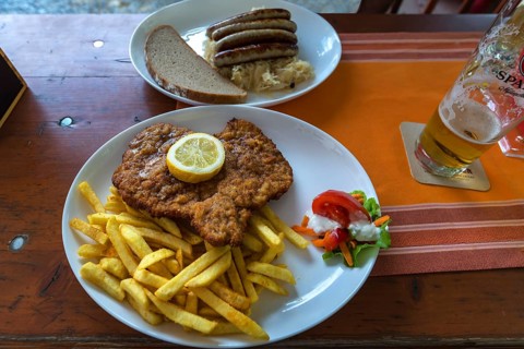Wiener schnitzel with French fries and bratwurst with sauerkraut served in a beer garden, Bavaria,