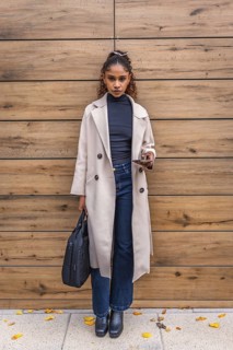 Vertical full length portrait of a stylish African american businesswoman leaning on a wooden wall