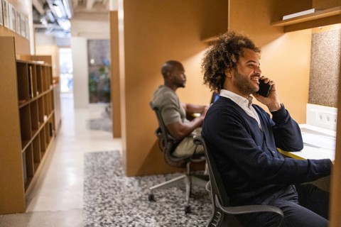 Two professionals engaged in work at a coworking space in Barcelona. One person is smiling on the