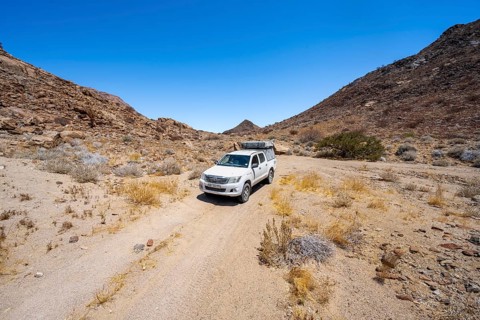 Toyota Hilux off-road vehicle on a sandy track, desert landscape with Brandberg, Erongo,