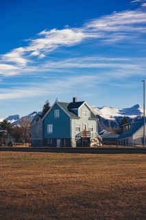 Traditional Icelandic house with a teal-blue facade and red accents stands in front of a