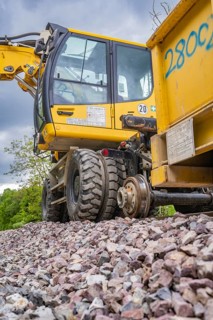 Close-up of a large yellow construction machine on a building site with large tyres and gravel,