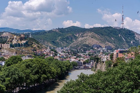 A breathtaking view of Tbilisi showcasing the scenic beauty of its lush green hills, historic