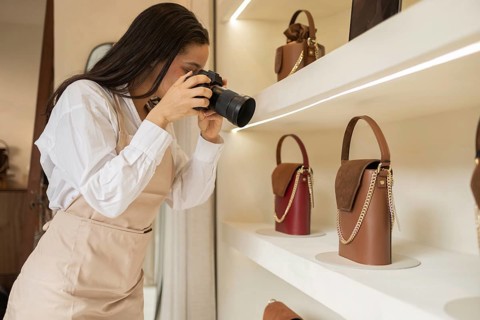 A photographer takes detailed shots of elegant handbags on display in a boutique store. Various
