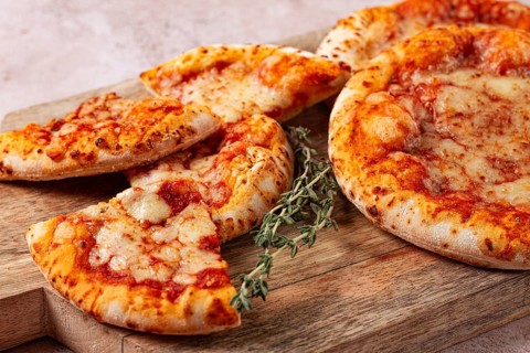 Four pizzetta Margaritas, on a cutting board, on a light gray surface, top view