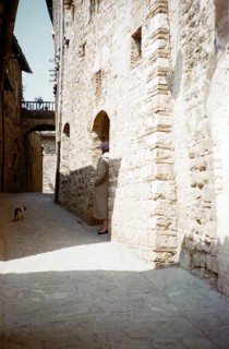 A tourist tries to make friends with a cat in an Italian village alley, Italy, 1957