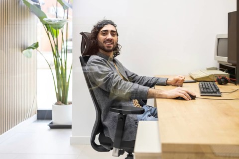 A professional working at a desk in a modern office setting, featuring a computer, wooden