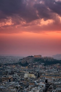 A breathtaking view of Athens at sunset, featuring the Parthenon and Acropolis illuminated against